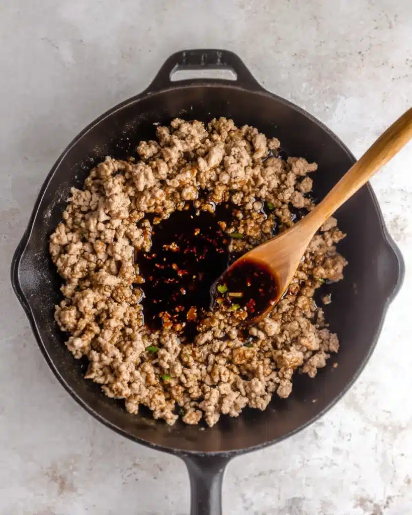 Soy sauce and honey added to browned ground pork in skillet