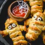 Golden puff pastry sausage mummies with edible eyes and spiderweb dip