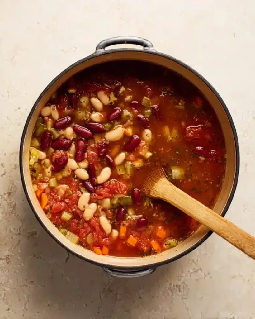 Beans added to simmering tomato broth and vegetables for minestrone soup