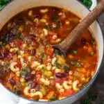 Hearty minestrone soup with pasta, beans, and vegetables in a rustic pot