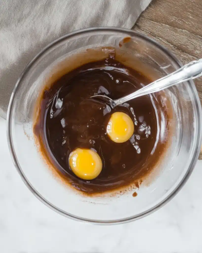 Mummy Brownies step with eggs added to chocolate mixture in bowl