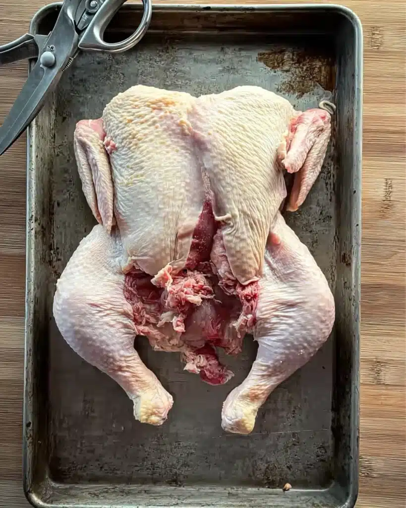 Spatchcocked chicken on a baking sheet prepared for Orange Chicken Roast with Fennel and Shallots