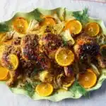 Orange chicken roast with fennel, shallots, and citrus garnish on a serving platter