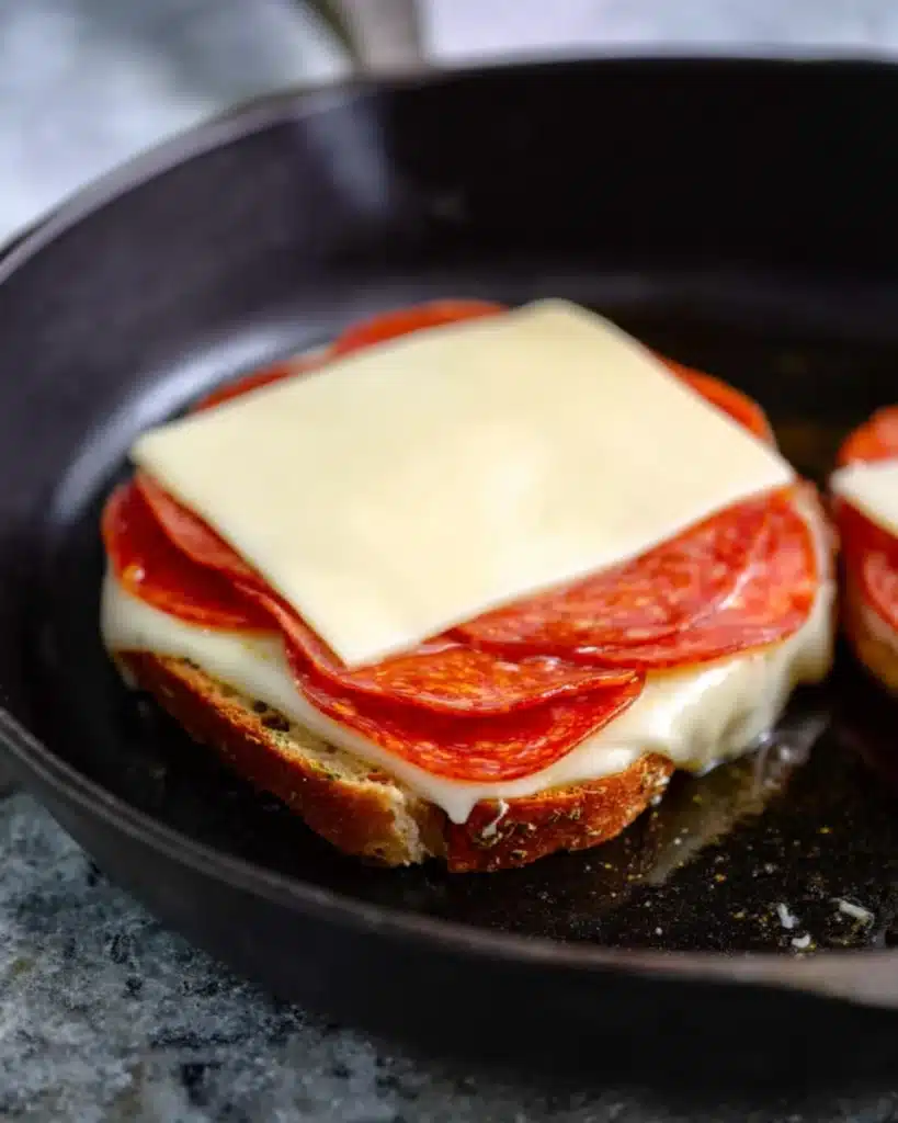 Pizza grilled cheese sandwich in skillet layered with pepperoni and mozzarella