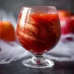 Finished poisoned apple cider Halloween cocktail with golden shimmer in a glass