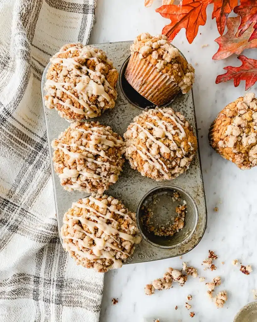 Pumpkin cinnamon streusel muffins in pan with glaze drizzle