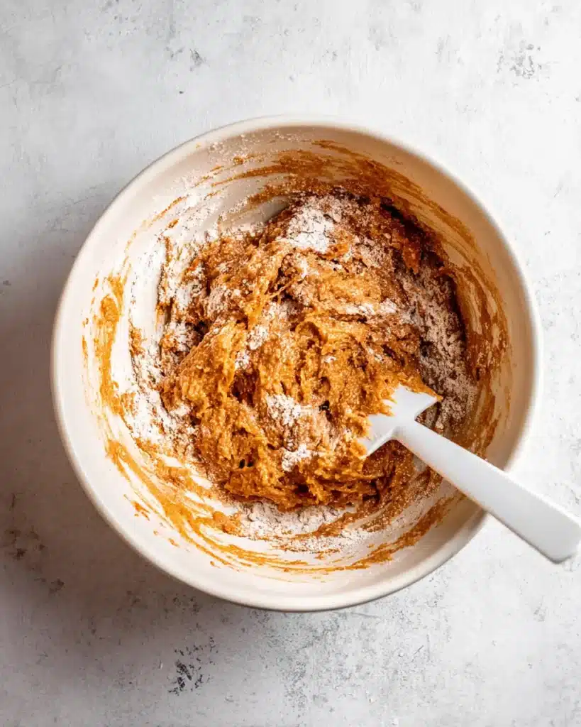Partially mixed pumpkin muffin batter with flour streaks