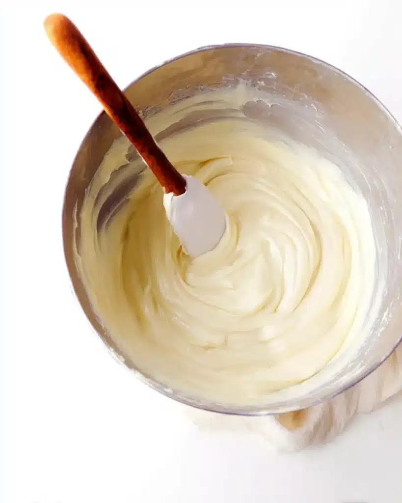 Mixing bowl with cream cheese frosting and spatula