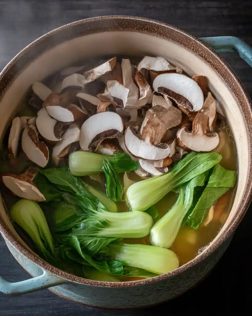 Pot of wonton soup with shiitake mushrooms and fresh bok choy