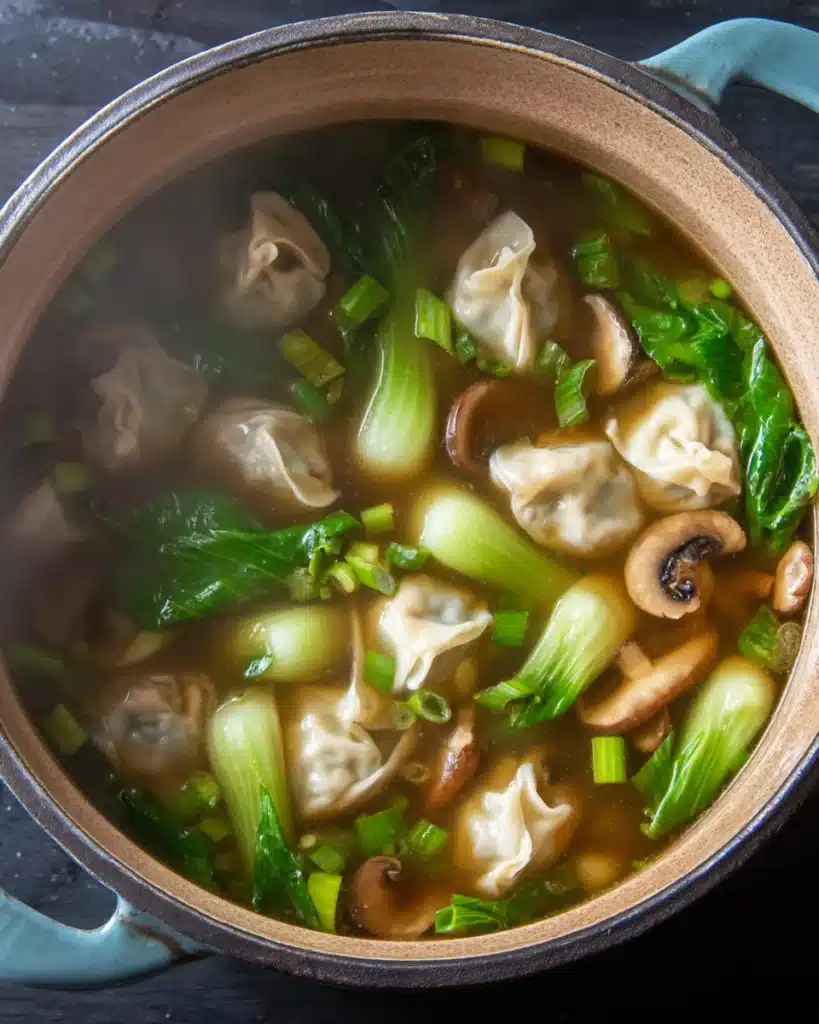 Pot of quick and easy wonton soup with dumplings, bok choy, and mushrooms