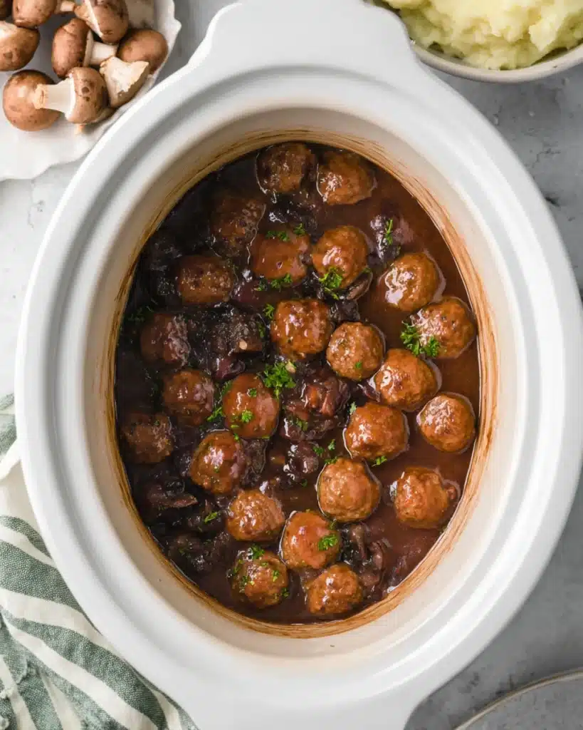 Cooked Salisbury steak meatballs in mushroom gravy inside slow cooker