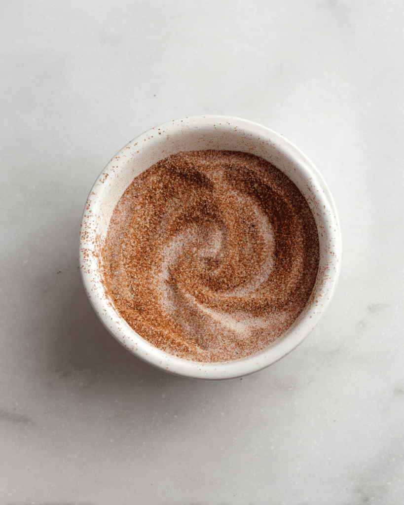 Cinnamon sugar mixture in a white bowl for pumpkin cookies