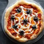 Spiderweb Halloween pizza with olive spiders on rustic crust