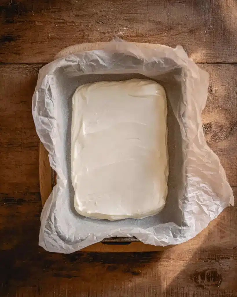 Melted white chocolate spread on parchment for Halloween Oreo bark