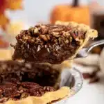 Slice of Texas chocolate pecan pie lifted from pan with gooey fudge filling