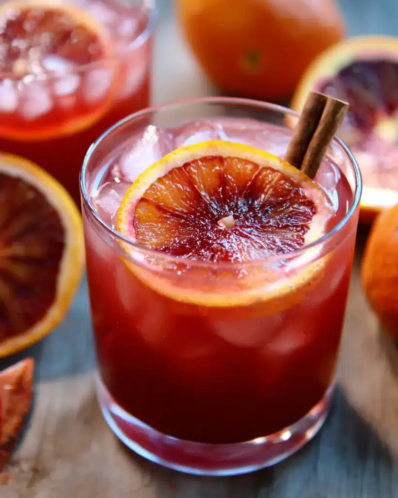 Cocktail-style Witches Brew punch with ice, orange slice, and cinnamon stick