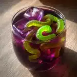 Halloween punch with gummy worms and ice in a glass