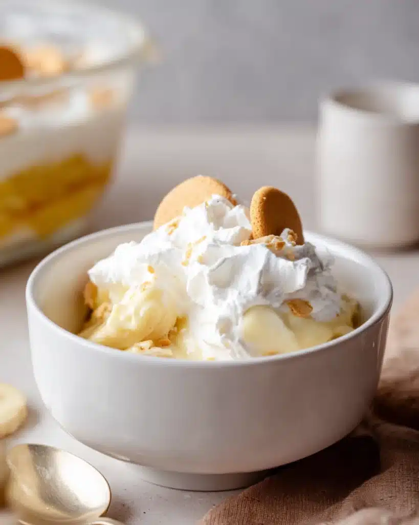 Serving of banana pudding with wafers and whipped cream in a white bowl