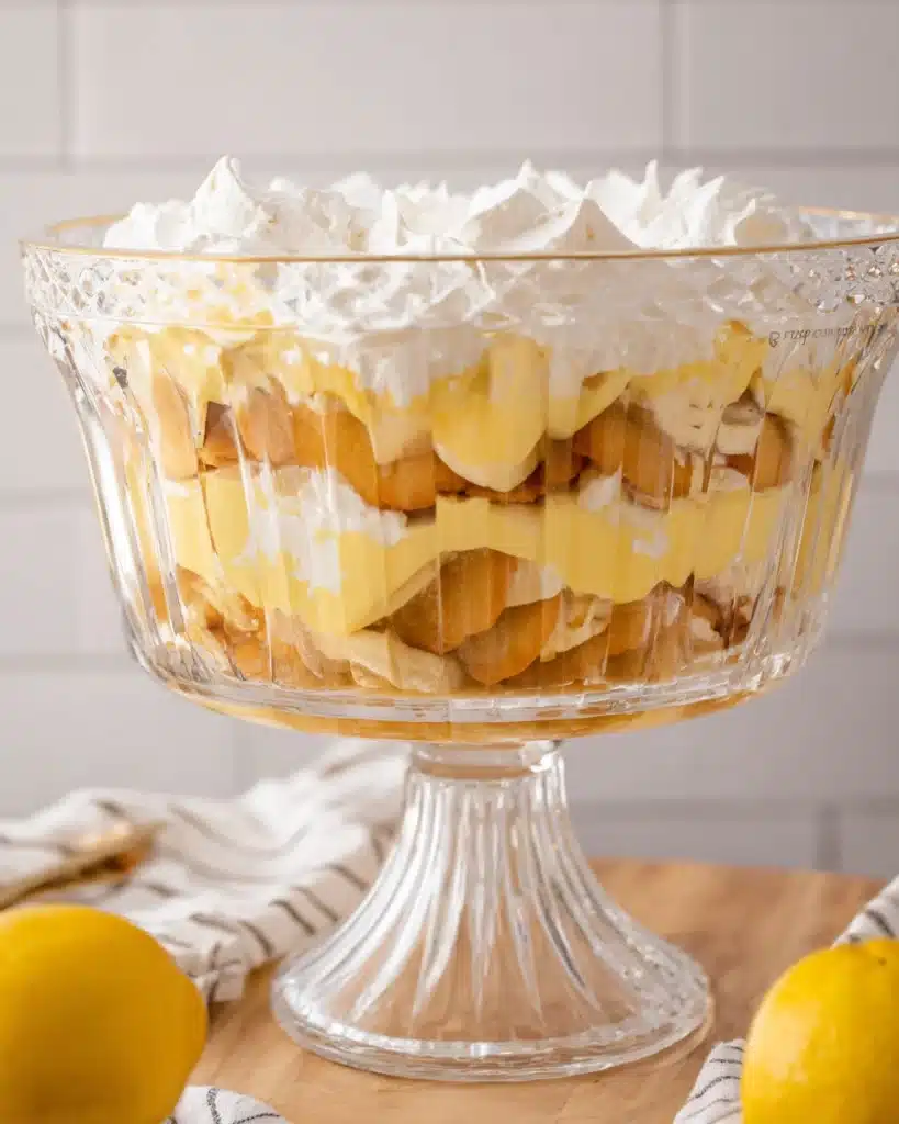 Banana pudding layers in a glass trifle bowl with wafers and whipped cream