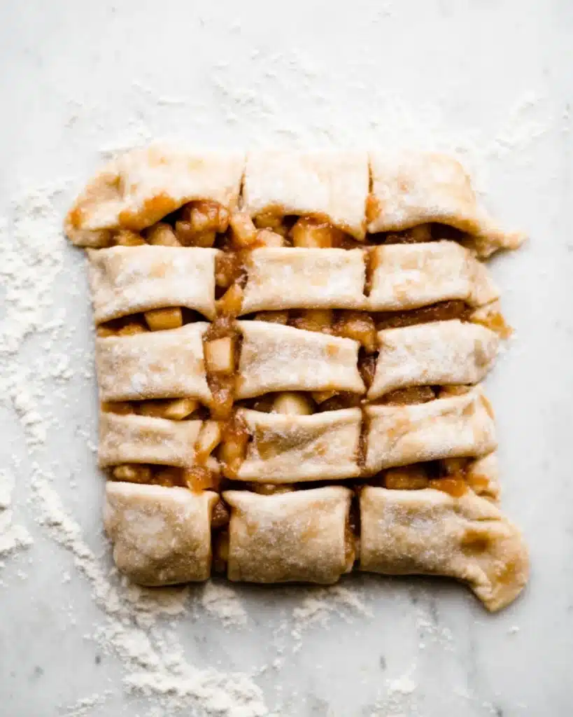 Cut apple fritter dough with caramelized apple filling on floured surface