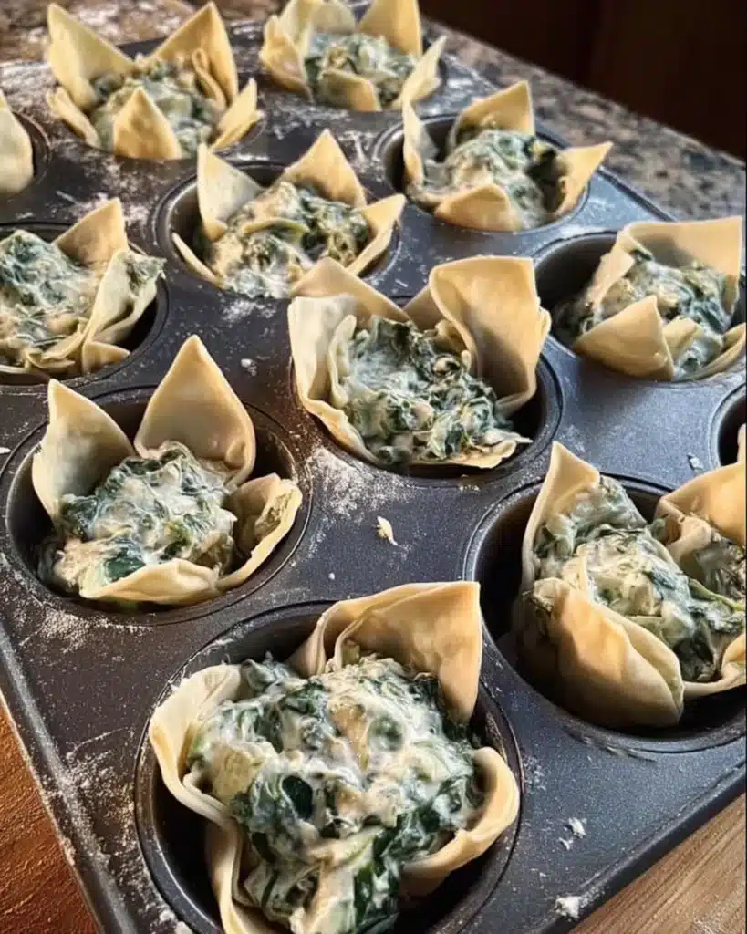 Unbaked spinach and artichoke wonton cups filled in muffin tin