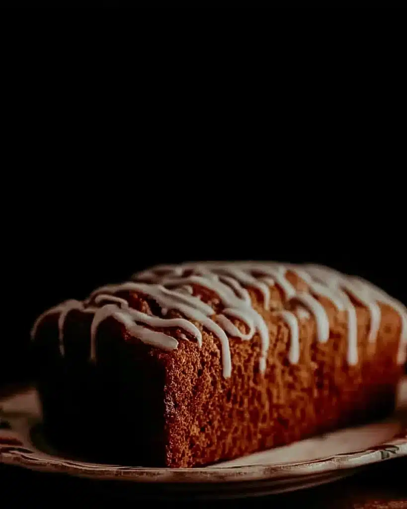 Whole Amish apple fritter bread loaf with vanilla glaze on a floral plate