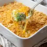 Baked broccoli cheese casserole with golden cracker topping being served