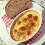Cheesy seafood casserole with brown bread on white plate