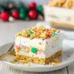 Festive Christmas cookie lasagna dessert with whipped layers, sprinkles, and cookie crumble topping