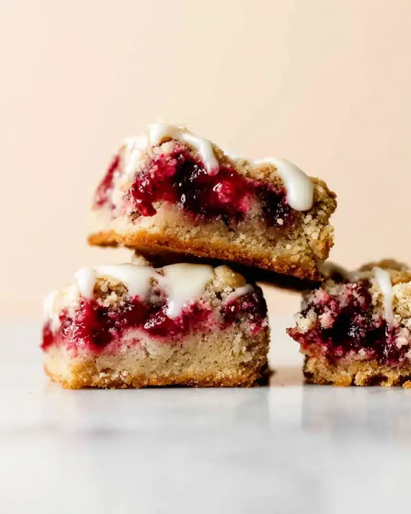 Close-up of stacked cranberry bars with crumble topping and icing drizzle