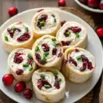 Cranberry roll ups with cream cheese and cranberries on a white plate