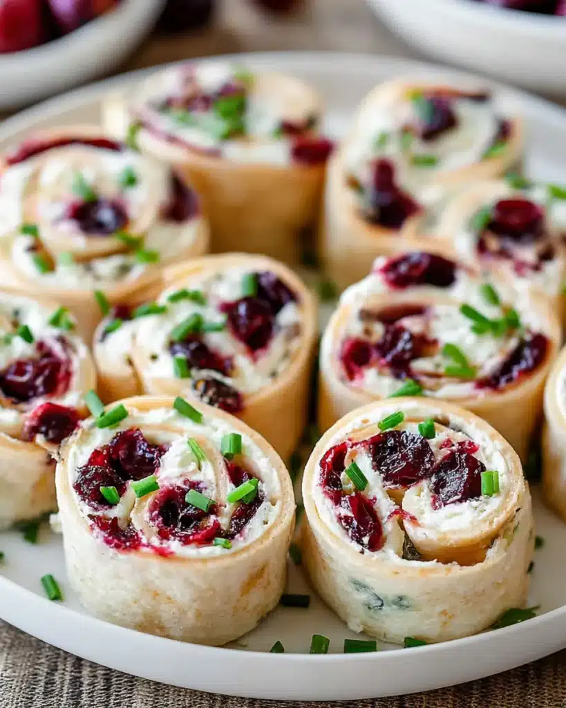 Cranberry roll ups with cream cheese and chives on a white plate