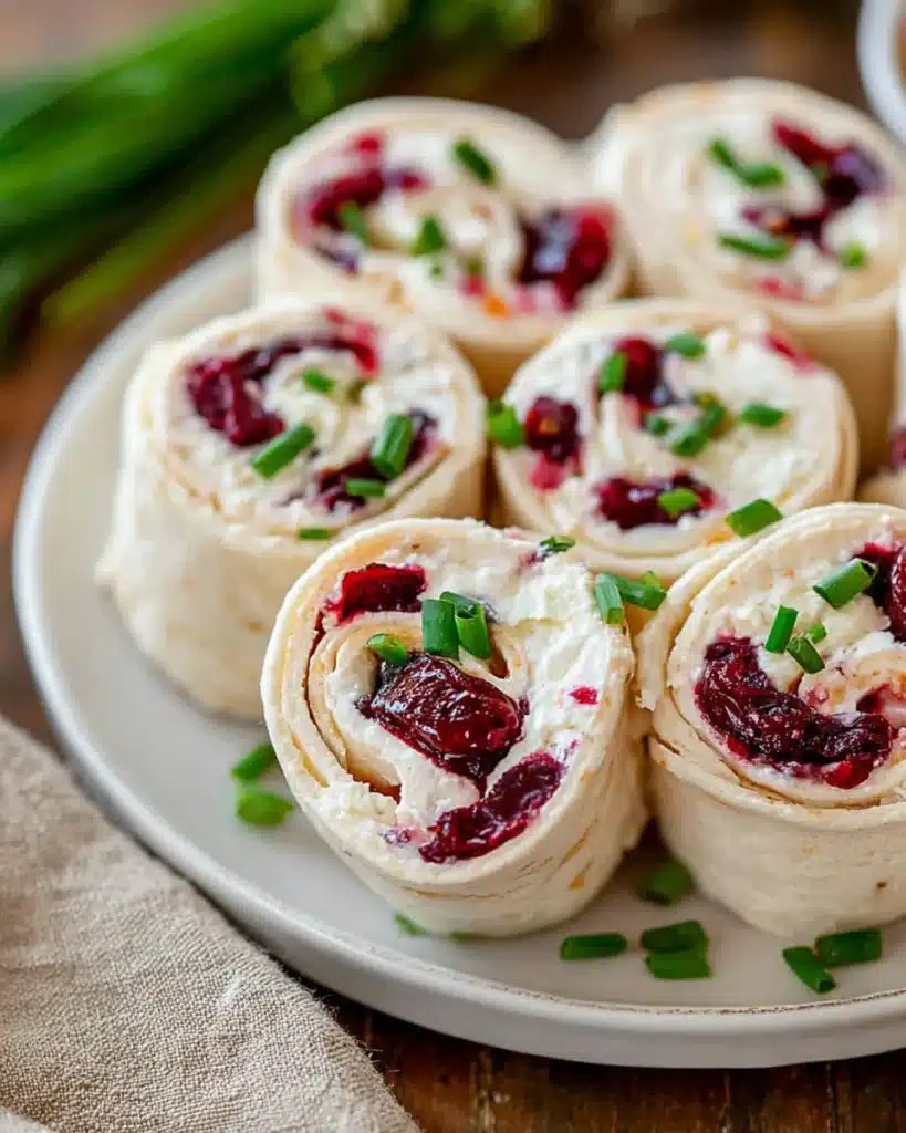 Cranberry roll ups with creamy cheese and chives on a white serving plate