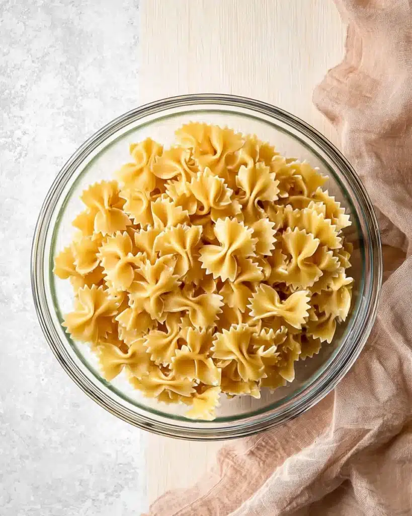 Cooked farfalle pasta in a glass bowl for fall harvest pasta salad