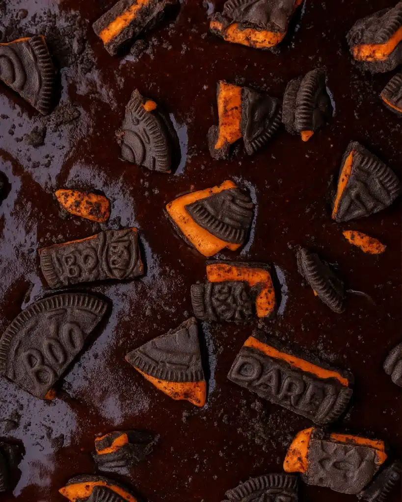 Brownie batter topped with crushed Halloween Oreos and orange filling