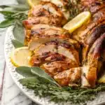 Sliced roast turkey with herbs and lemon wedges on a platter