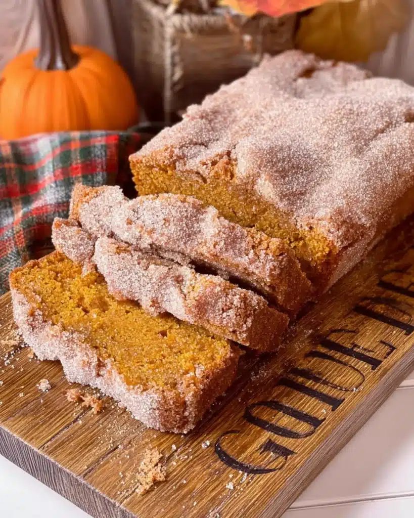 Sliced sweet potato bread loaf with cinnamon sugar crust on wooden board