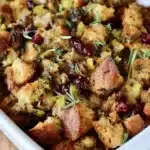 Golden-brown vegan stuffing with herbs and cranberries in a baking dish