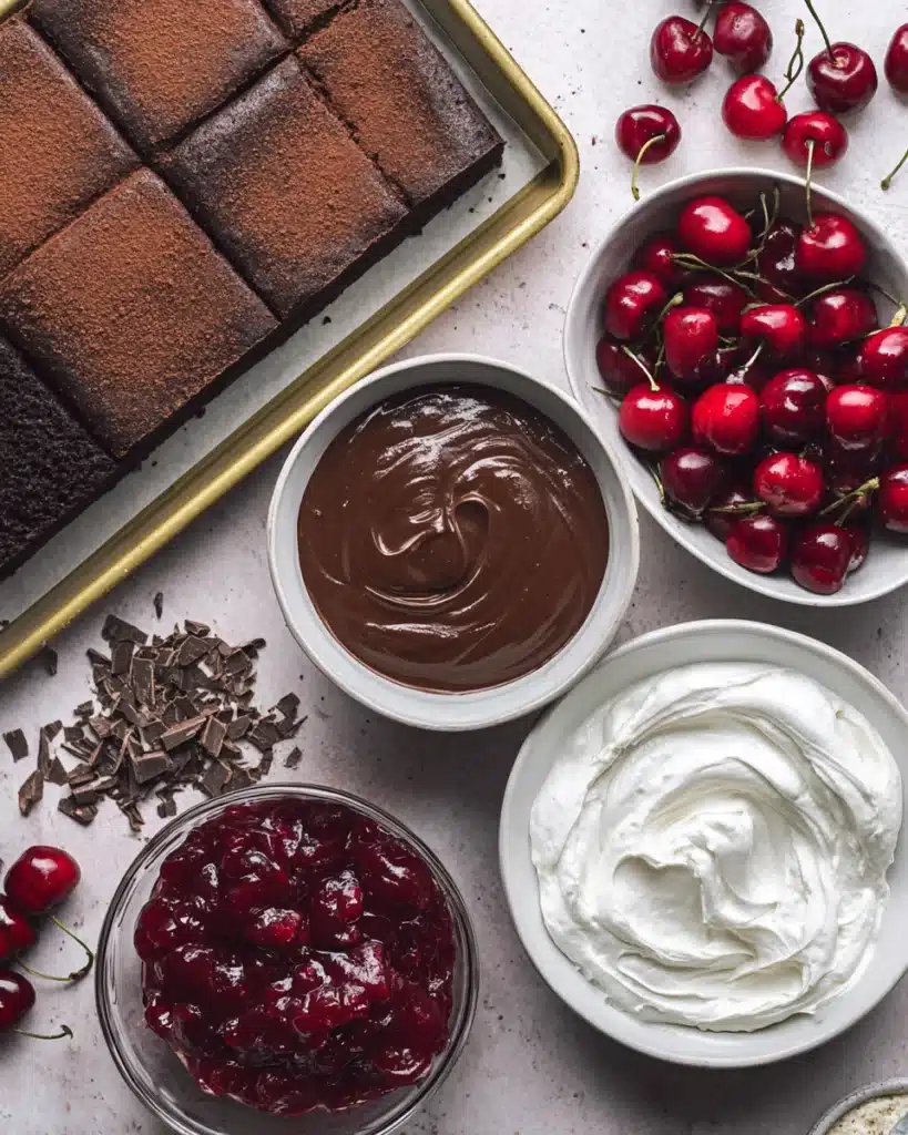 Black Forest Trifle ingredients with cake, cherries, pudding, and whipped cream on a countertop