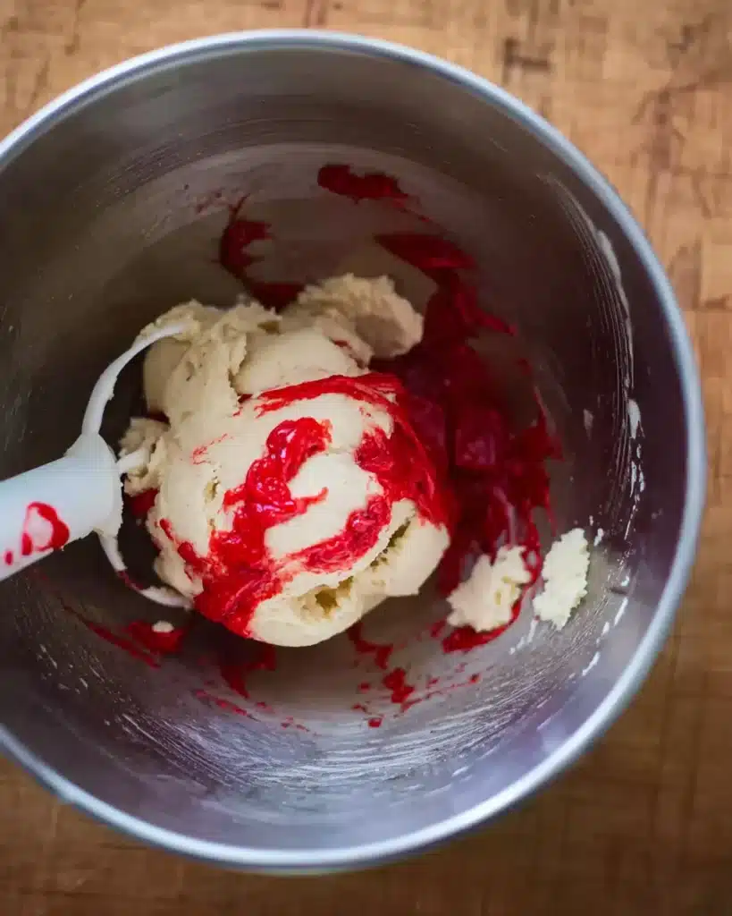 Cookie dough with red food coloring in a metal mixing bowl