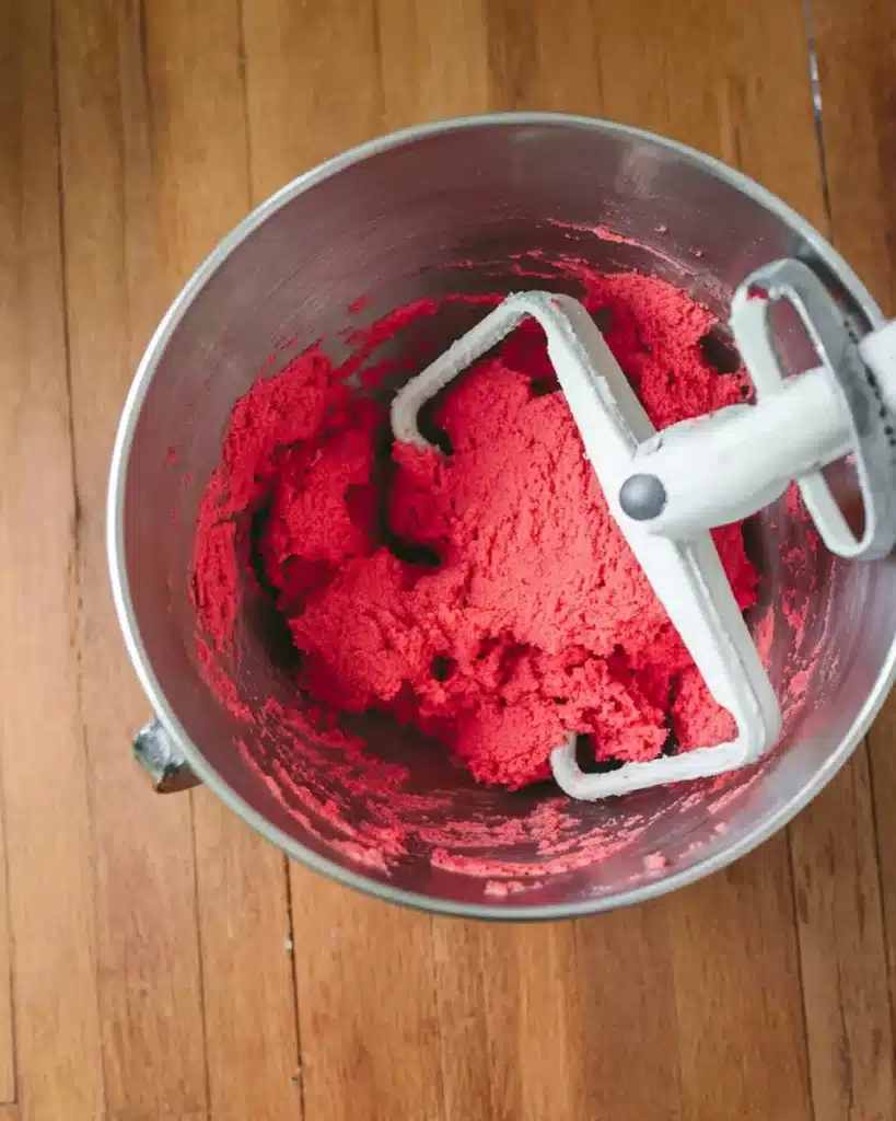 Red cookie dough mixed in a stainless steel bowl with paddle attachment