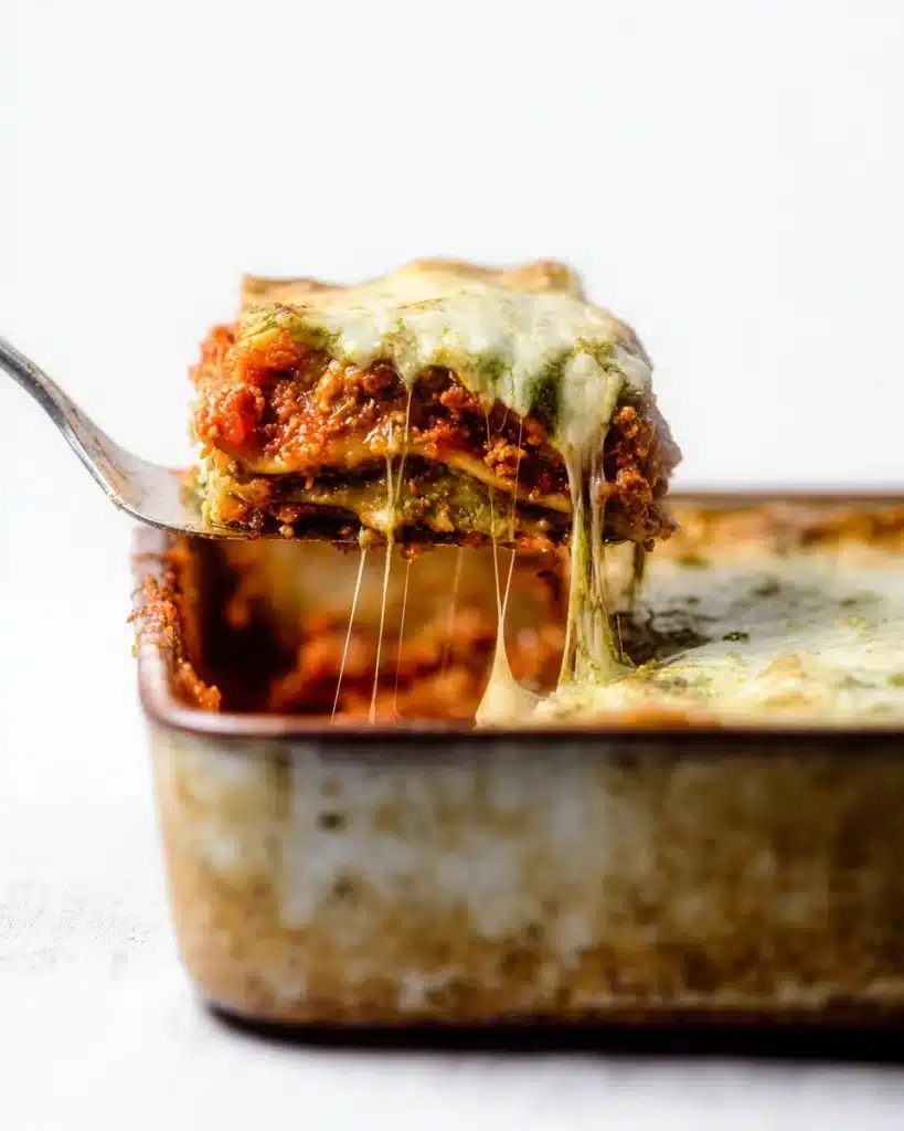 Cheesy Christmas Eve lasagna slice lifted from pan with melted layers