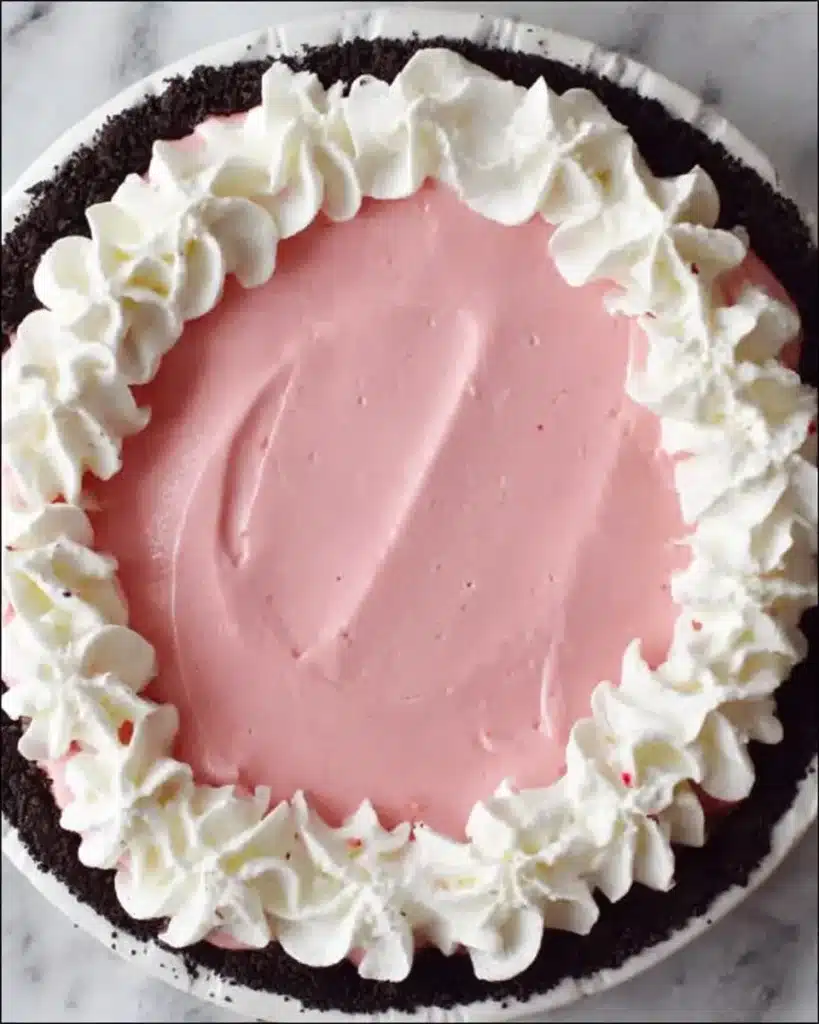 No-bake Christmas Peppermint Pie with pink filling and whipped cream border