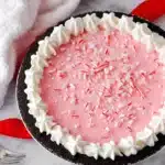 Pink Christmas peppermint pie with whipped cream border and crushed candy canes