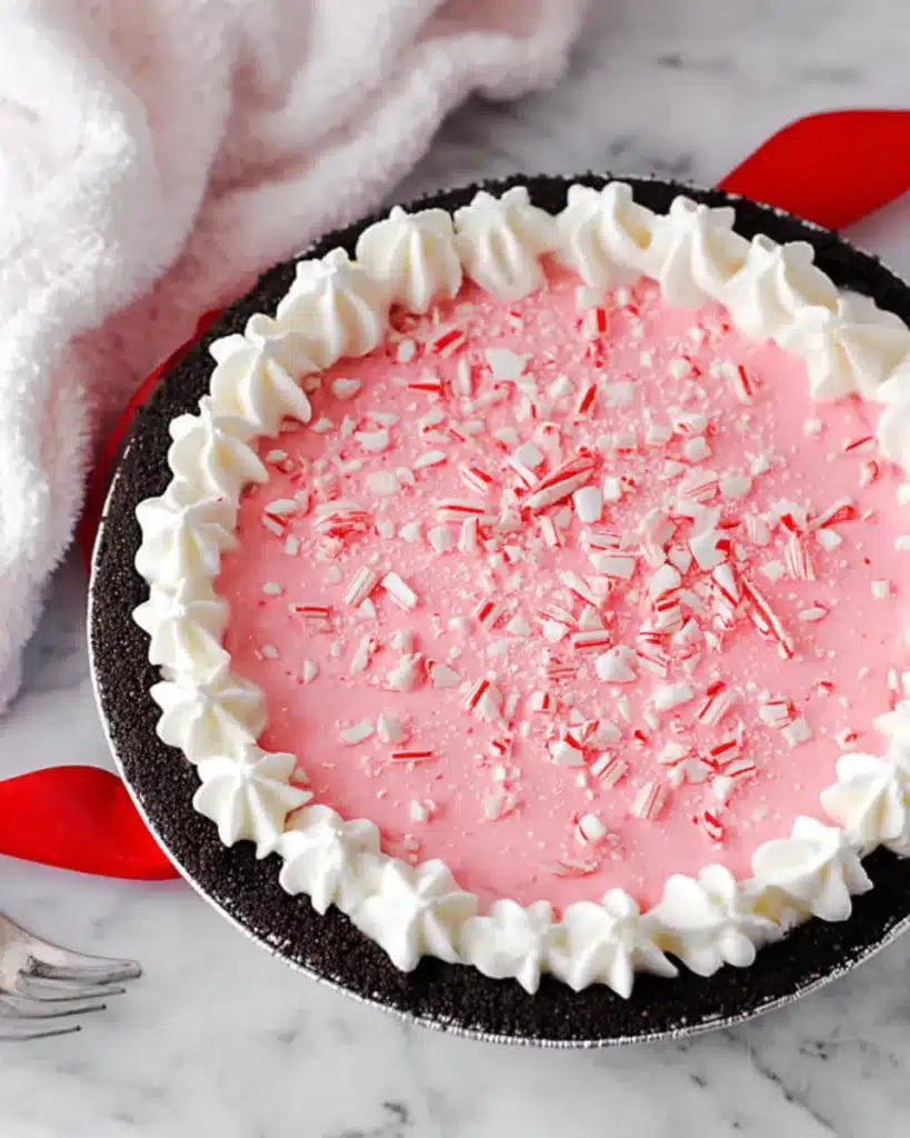 Pink Christmas peppermint pie with whipped cream border and crushed candy canes