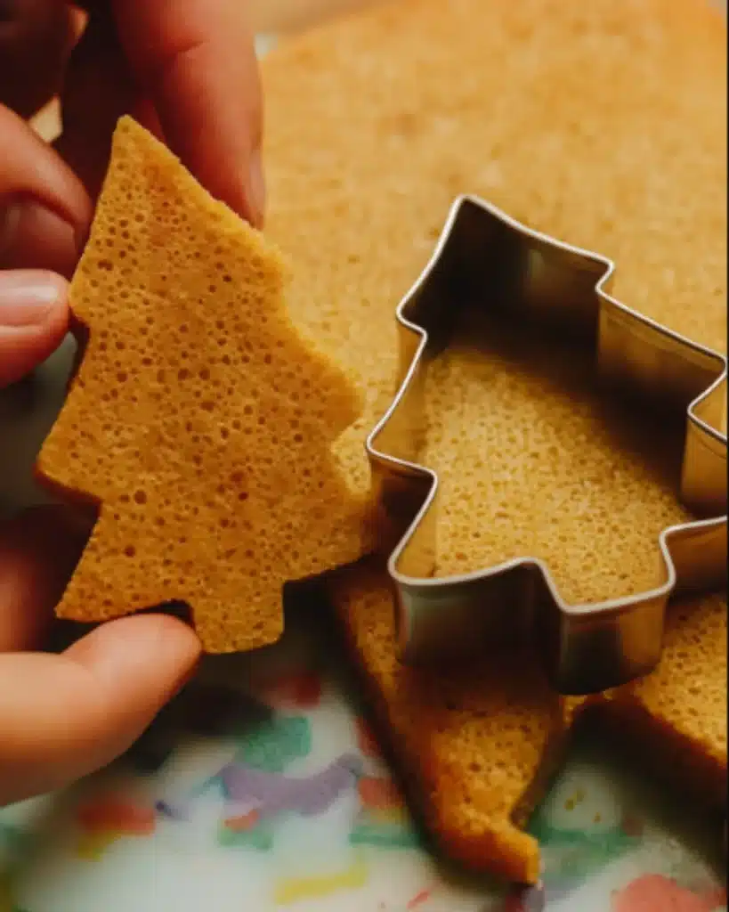 Christmas tree-shaped sponge cake cutouts on a colorful cutting board