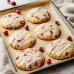 Cranberry orange cookies with icing on baking tray beside Christmas Tree Cupcakes
