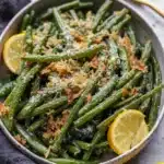 Garlic Parmesan roasted green beans with crispy garlic and melted cheese in a ceramic bowl