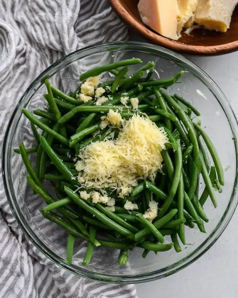 Fresh green beans with garlic and parmesan in a mixing bowl