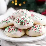 Frosted Italian Christmas cookies with red, green, and white sprinkles on a white plate